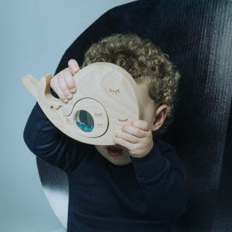Child holding a wooden toy shaped like a heart against a blue background
