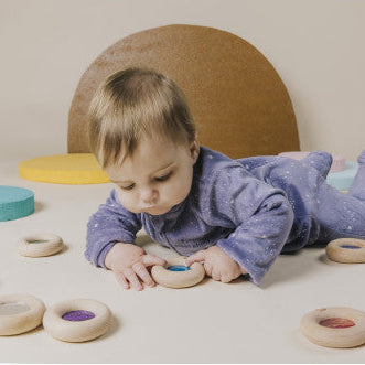 Child playing with colorful circular toys on a light surface.