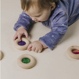 Child playing with colorful wooden toys on a light surface